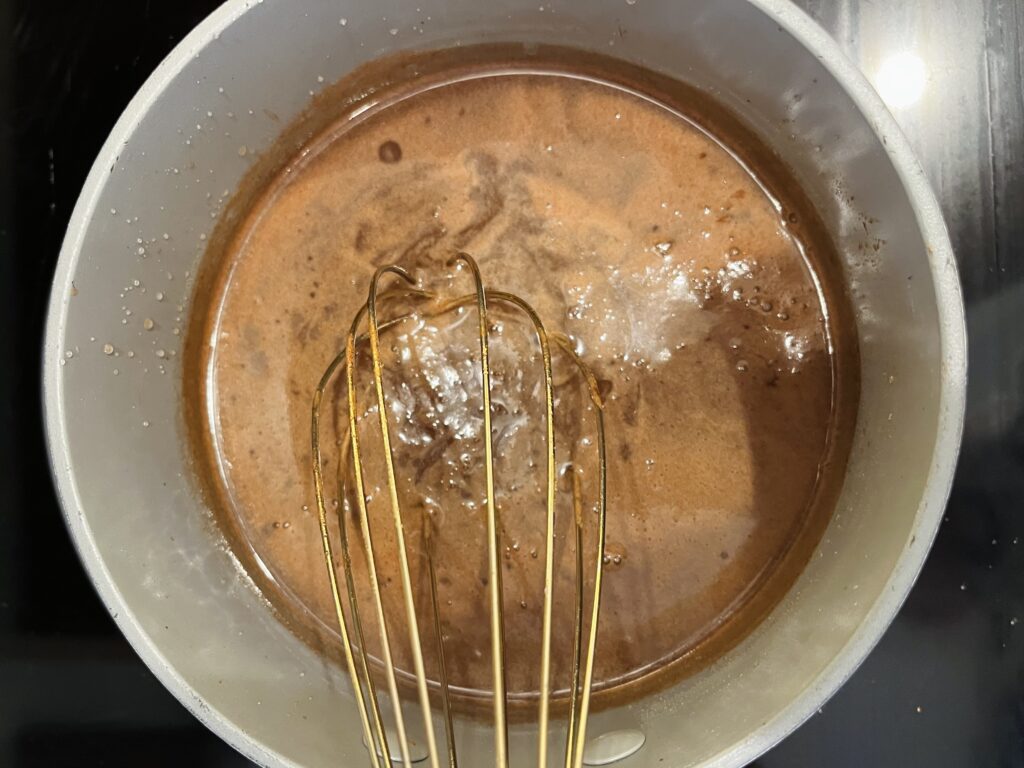 whisking sugar syrup in a small pot on the stove
