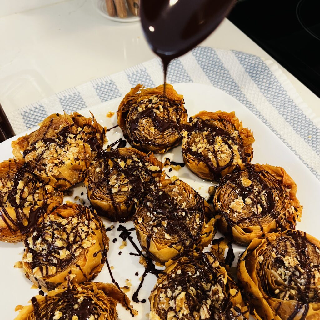 Drizzling dark chocolate onto of finished phyllo pieces on a plate