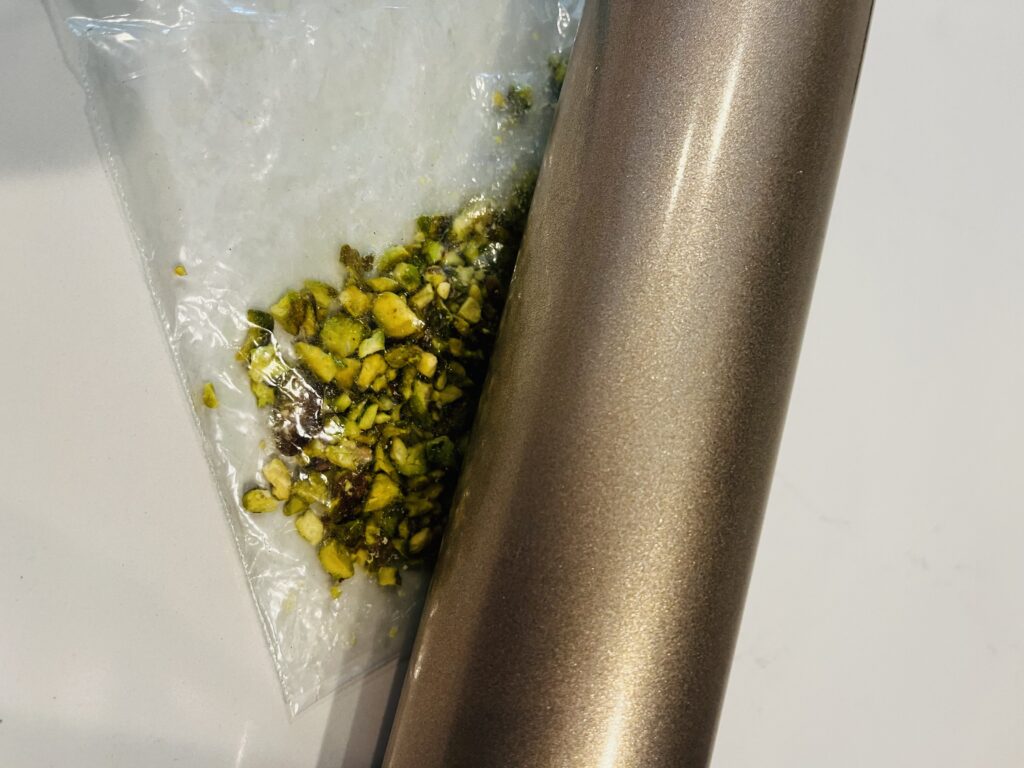 Use a rolling pin to crush nuts inside of a ziploc bag on the counter