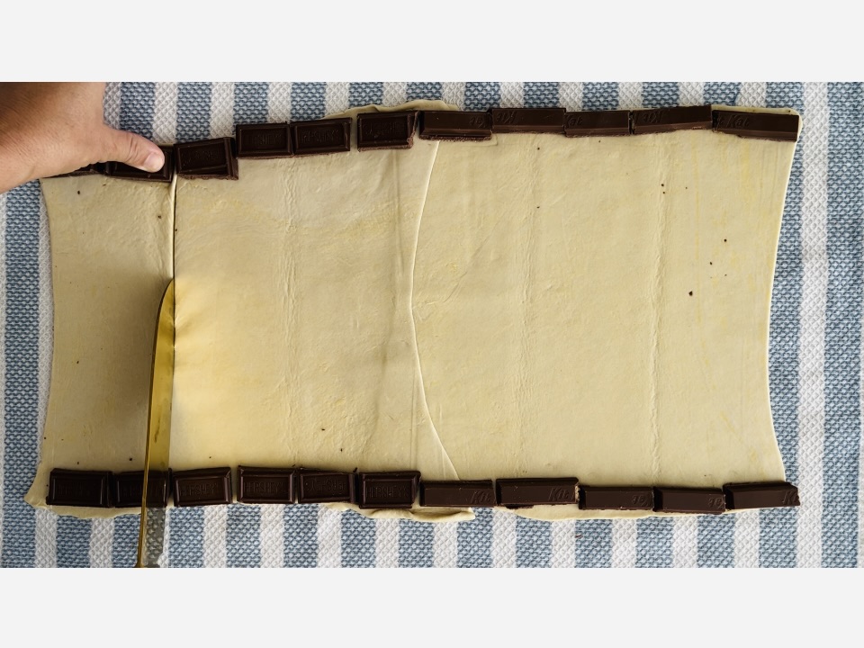 Cutting puff pastry lengthwise on a kitchen towel