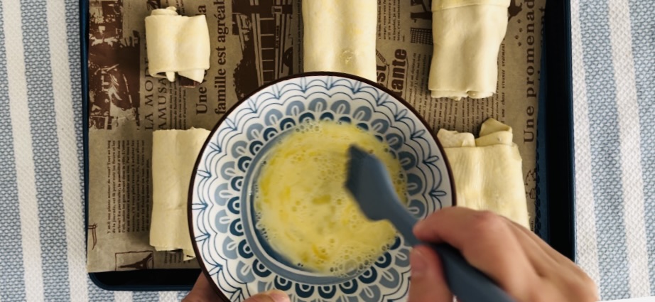 Using a basting brush apply egg wash to puff pastry on a parchment paper lined baking sheet