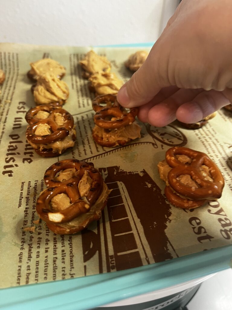 Placing a pretzel on top of the nutter butter mixture on a parchment lined baking sheet