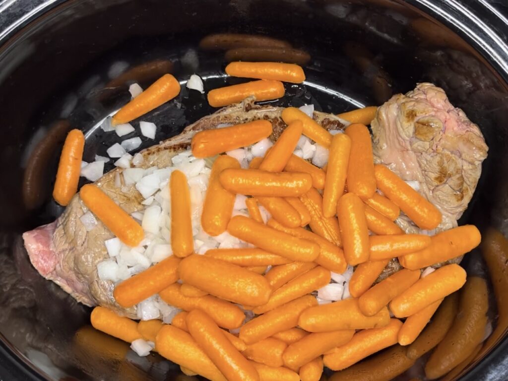 carrots, onion and beef in slow cooker in a slow cooker