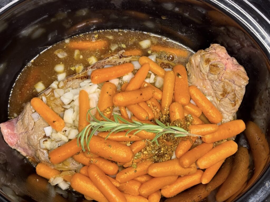 Beef, vegetables, water and seasoning mix over beef and vegetables in the slow cooker