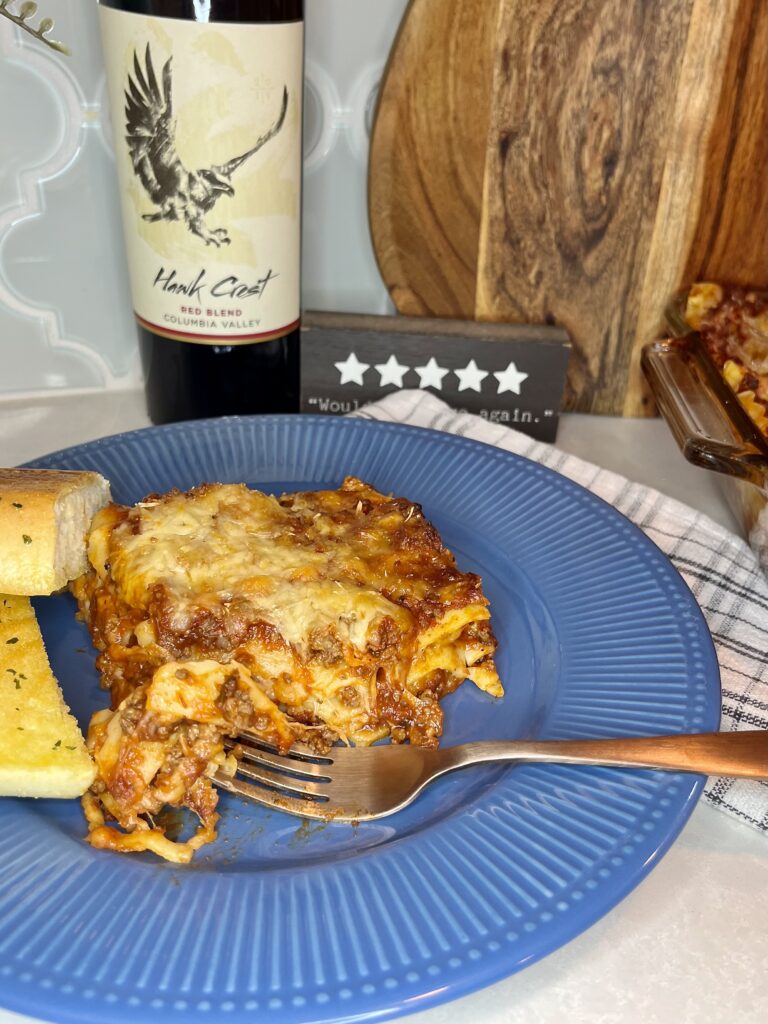 Cooked lasagna on a blue plate with garlic bread