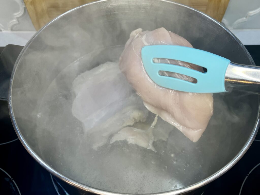 raw chicken being added to a pot of boiling water