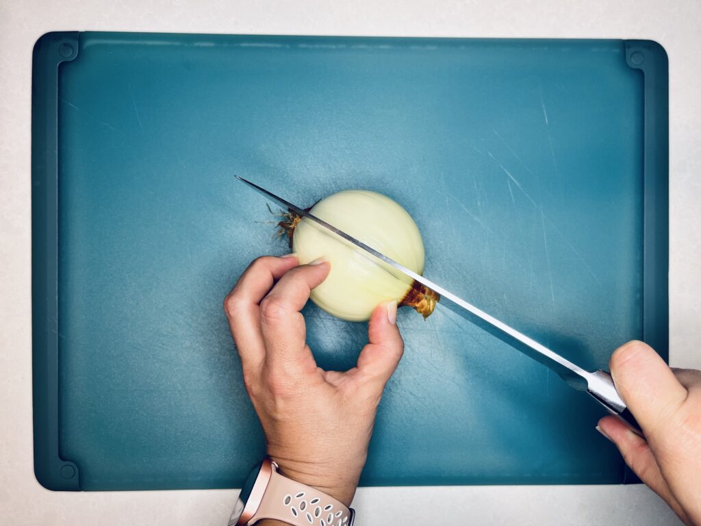 a knife slicing an onion in two halves