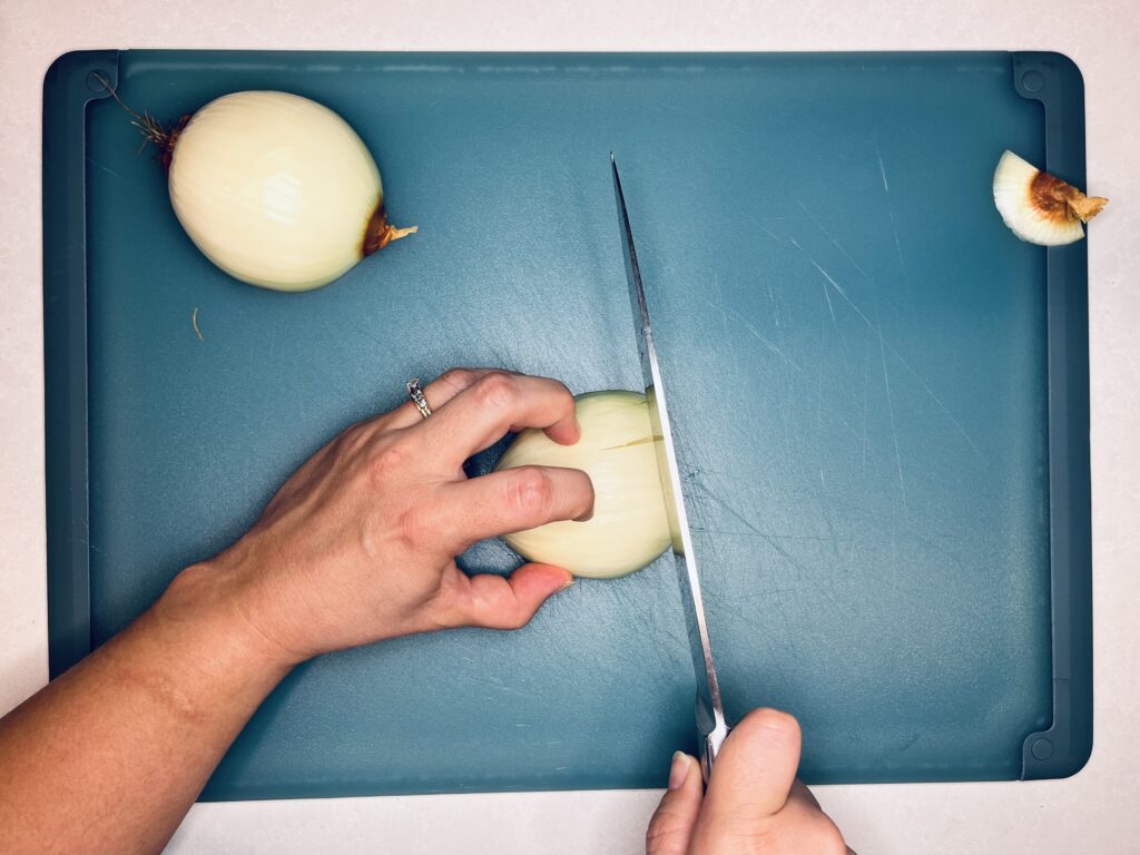 a knife making perpendicular slices in an onion