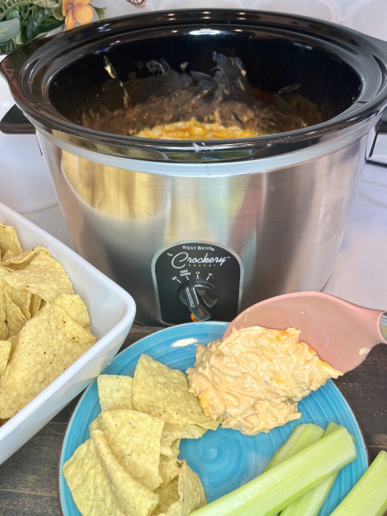 dip being served on a plate with chips and celery