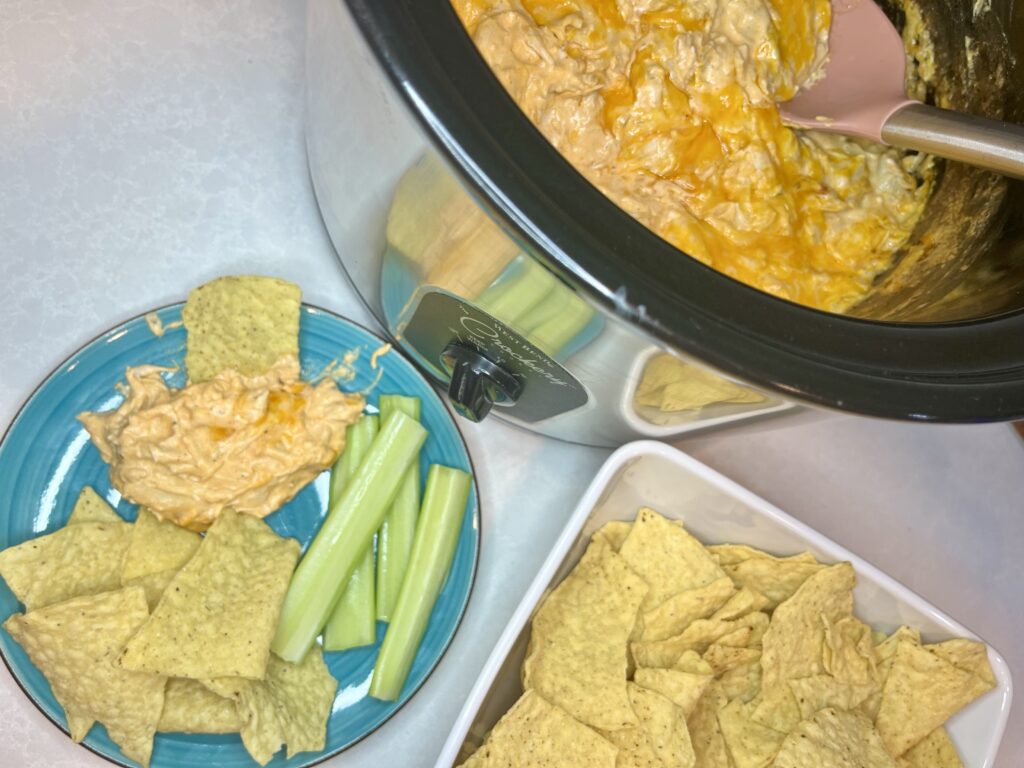 hot dip in a slow cooker next to a bowl of chips