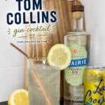 Refreshing Tom Collins gin cocktail with lemon garnish, served in a clear glass, alongside a bottle of organic gin and a can of LaCroix sparkling water, on a wooden cutting board background.