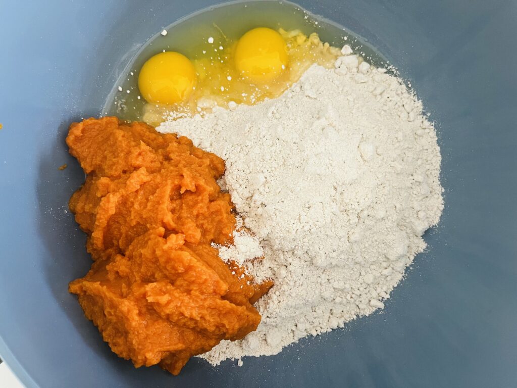 Spice cake mix, eggs and pumpkin in a mixing bowl.
