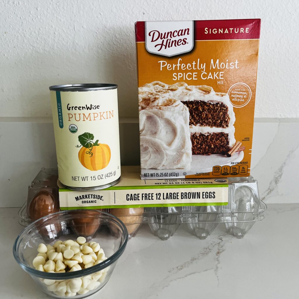 Canned pumpkin, spice cake mix, eggs and white chocolate chips on the counter