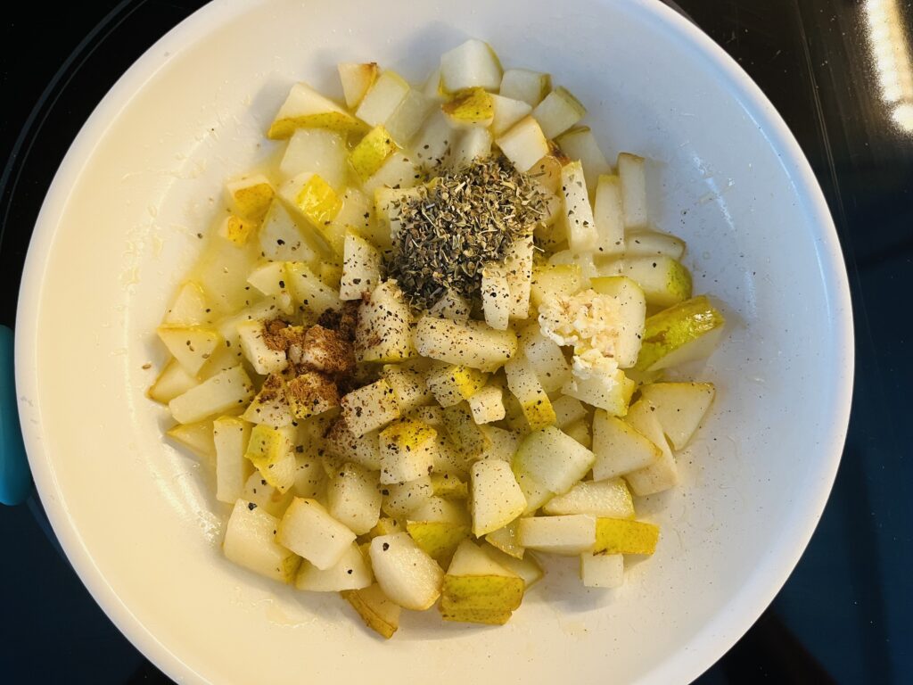 Cooked pear with garlic and seasonings in a small sauce pan on the stove.