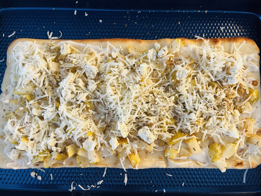 Flatbread topped with pears, and cheeses on a baking sheet