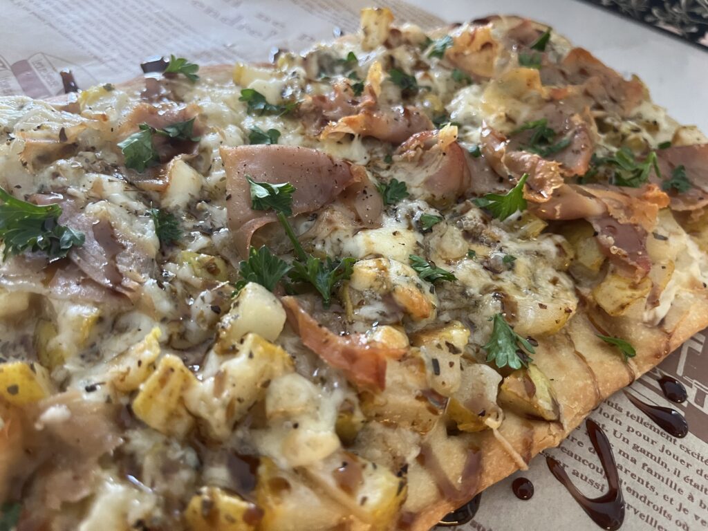 Prosciutto and Pear flatbread pizza with balsamic drizzle on parchment paper.