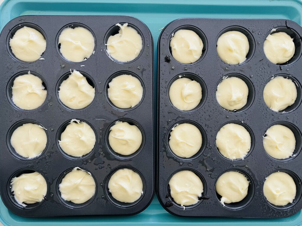 Brownie batter topped with peppermint cream cheese layer in mini muffin tins.