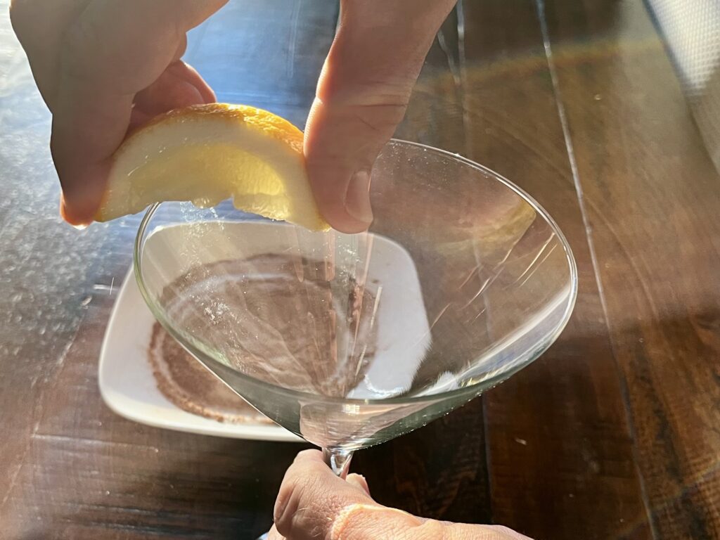 Rubbing a lemon wedge along the rim of the martini glass.