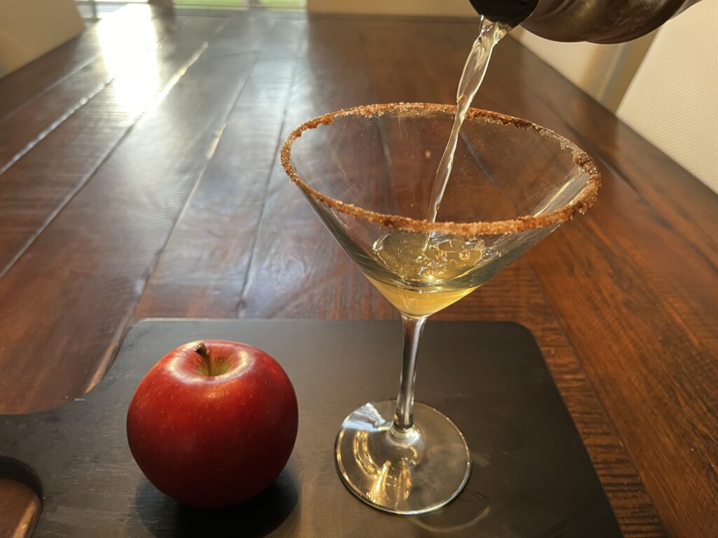 Pouring martini finished mixture into a martini glass.