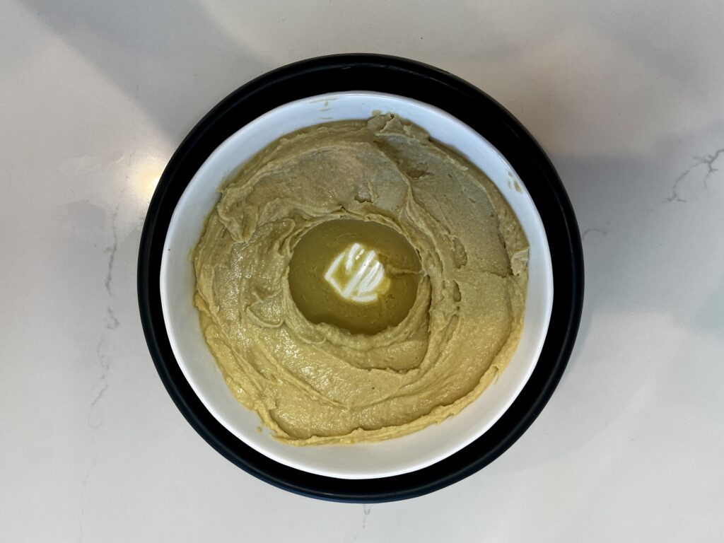 Hummus in a bowl with a hole in the center.