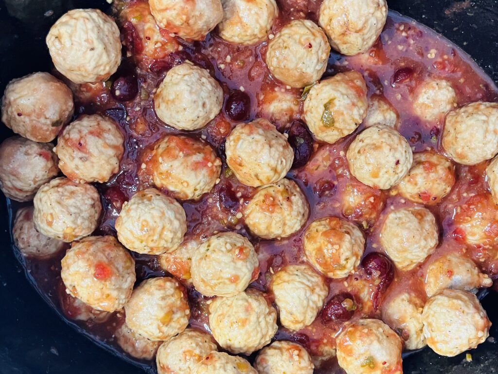 Frozen meatballs mixed with sauce in a slow cooker.