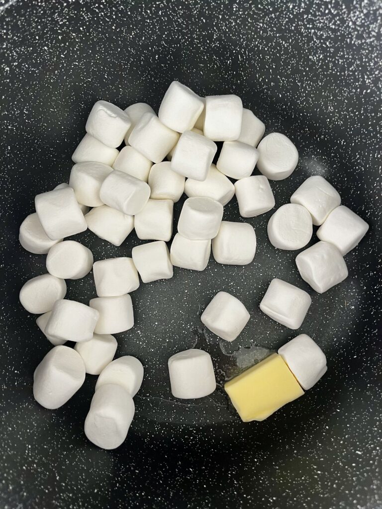 Large marshmallows and butter in a large pot on the stove.