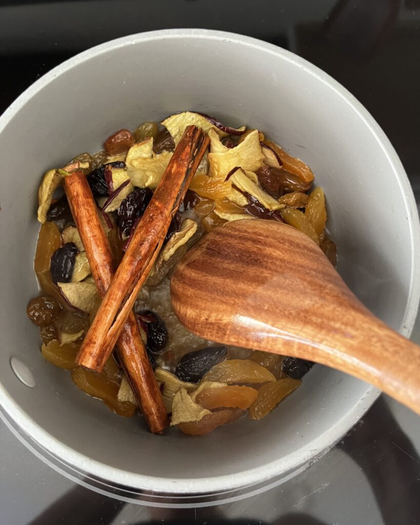 Fruit, honey, brandy and cinnamon sticks in a pot on the stove.