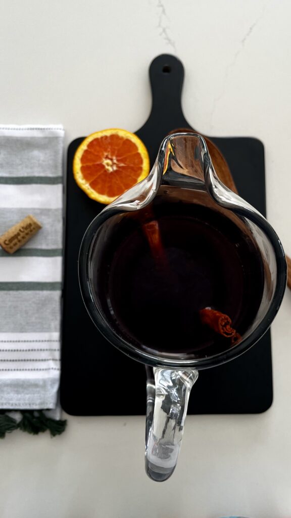 Red wine and brandy and dried fruit mixture in a pitcher on a black cutting board on the counter.