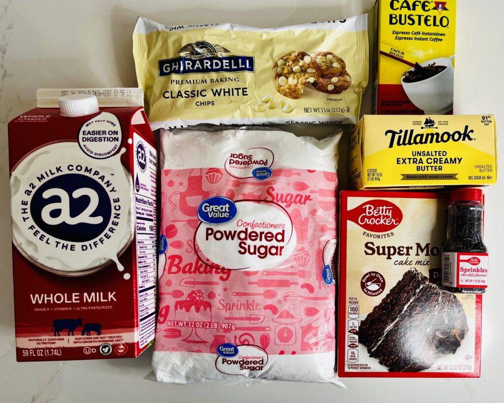 chocolate cake mix, chocolate sprinkles, whole milk, powdered sugar, white chocolate chip and instant espresso powder on the counter.