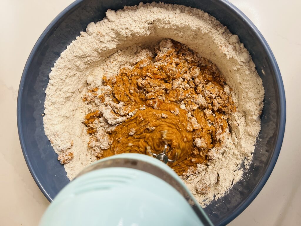 spice cake mix, eggs and pumpkin being mixed in large blue bowl on the counter