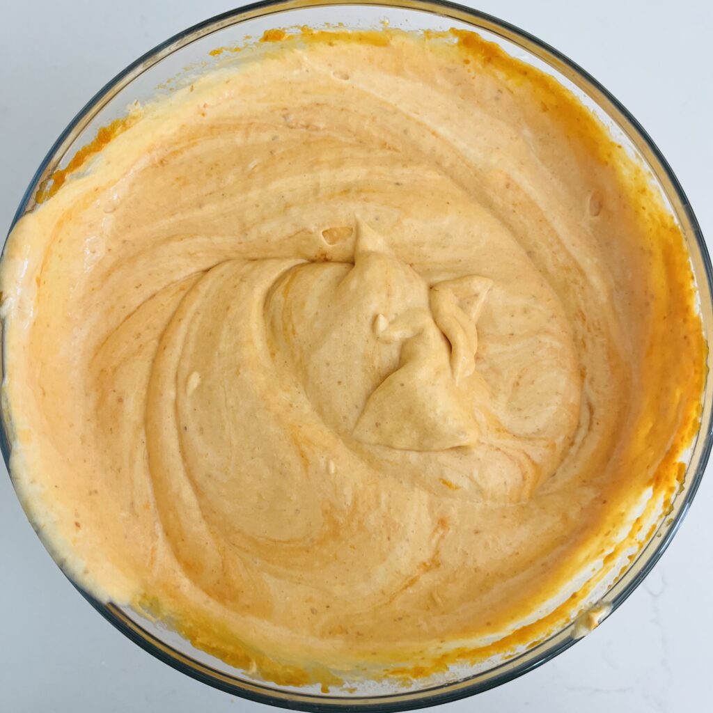 pumpkin and no bake cream cheese filling mixed together in a glass bowl on the white counter