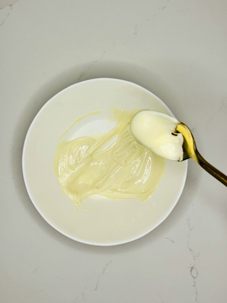 Melted white chocolate in a small white bowl on the counter.