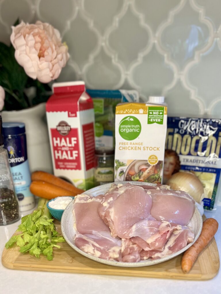 chicken thighs, onion, celery, carrots, chicken stock, gnocchi, half and half, spinach, salt and pepper, and flour on a counter