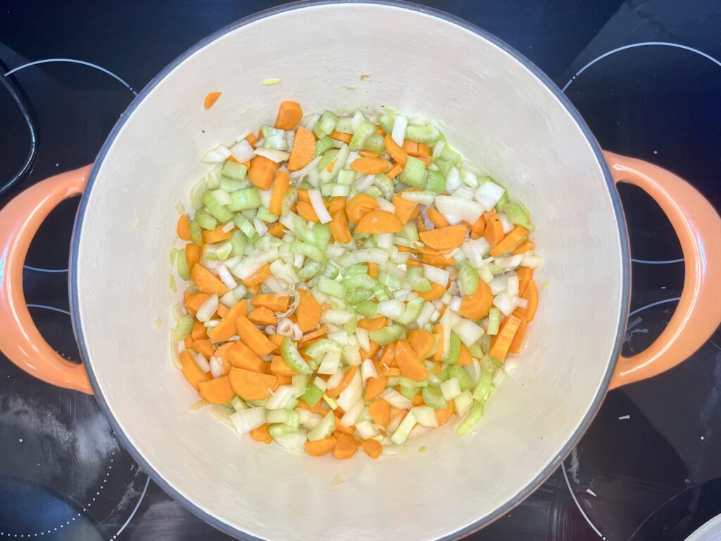 carrots, celery, and onion being browned in a pot