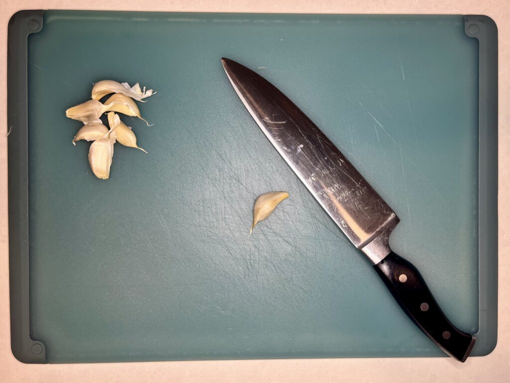 garlic bulbs on a cutting board with a knife