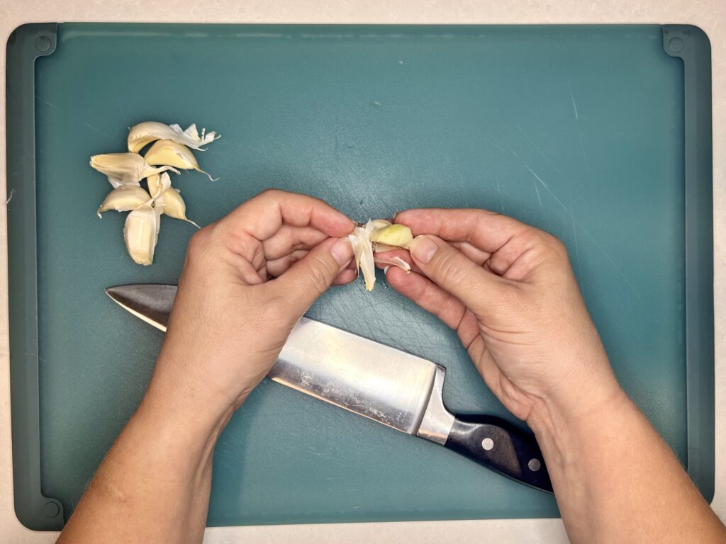 papery outer layer of garlic being removed