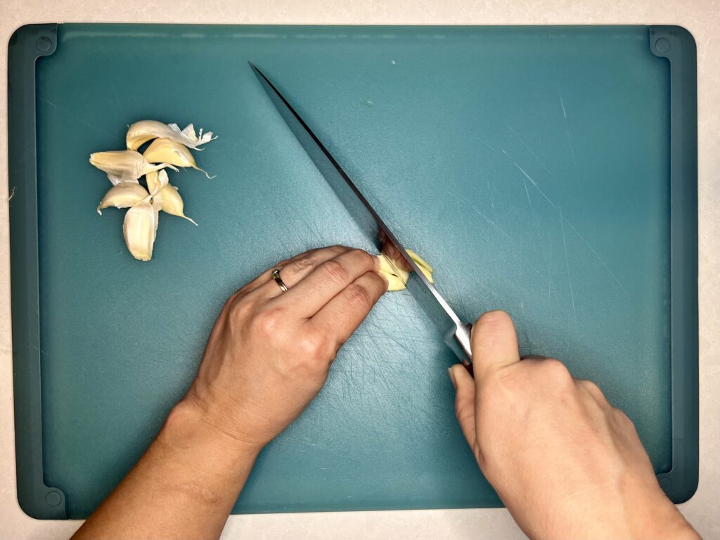 a knife slicing a garlic bulb