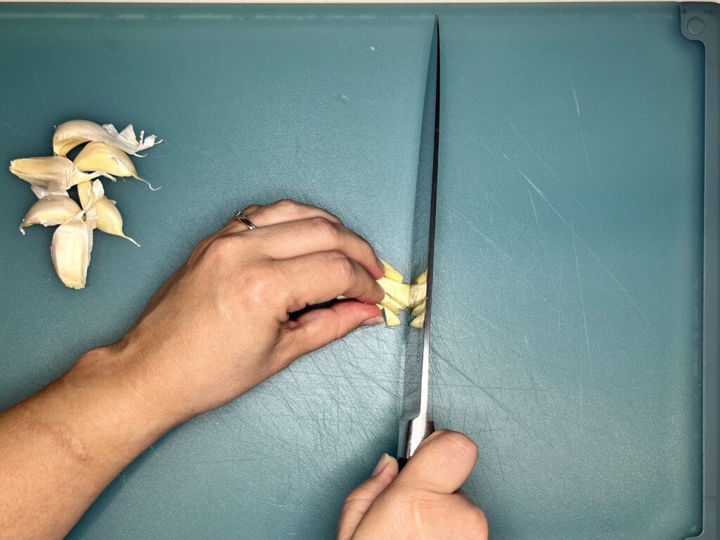 a knife continuing to slice through garlic