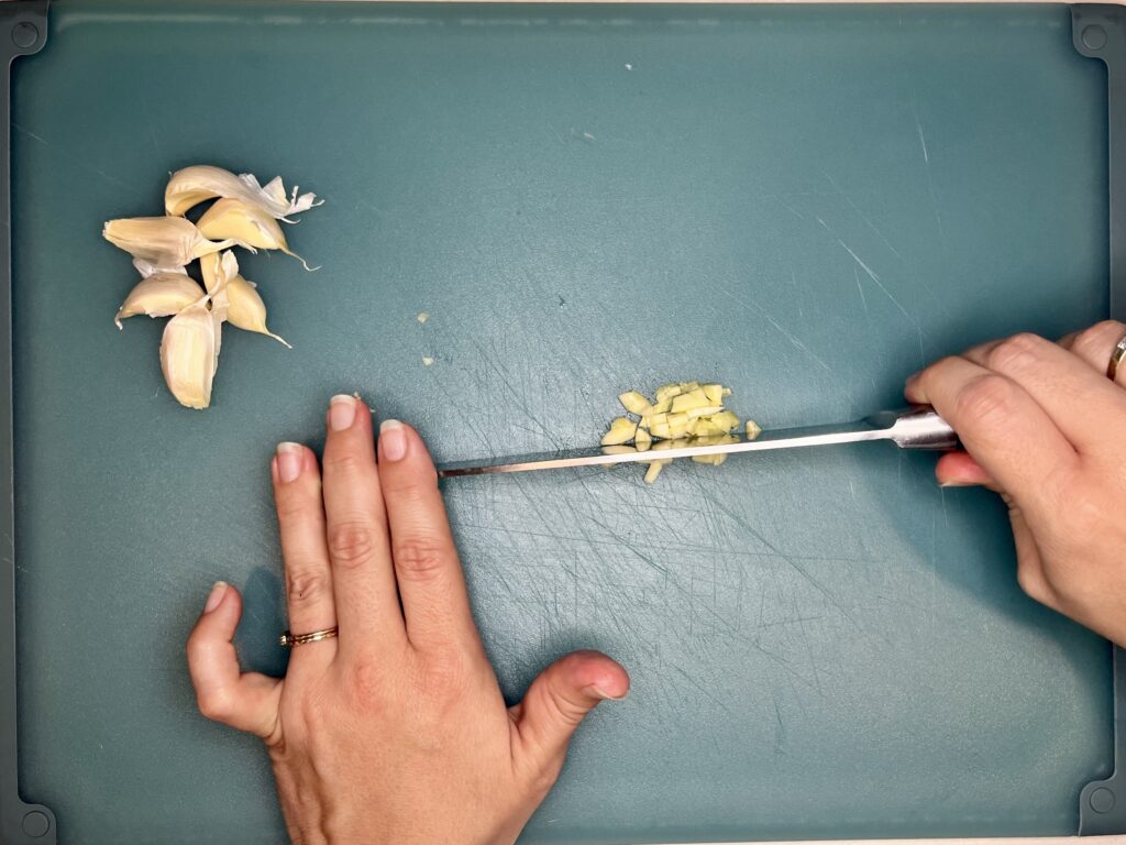 a knife rocking over garlic to mince