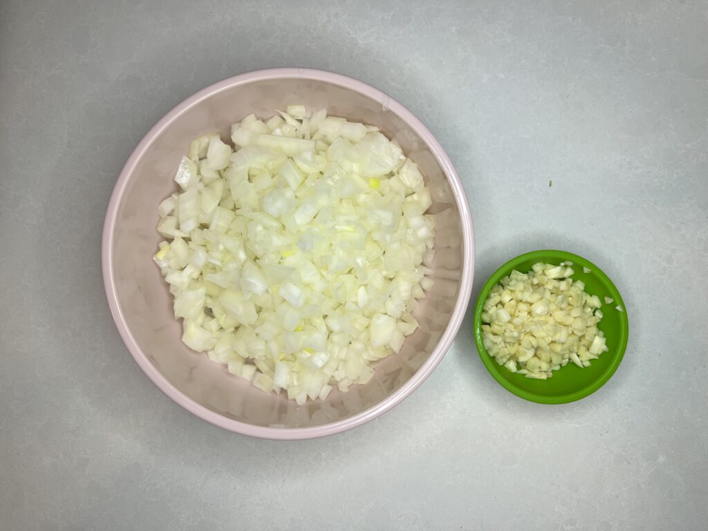 bowls holding minced garlic and finely diced onion