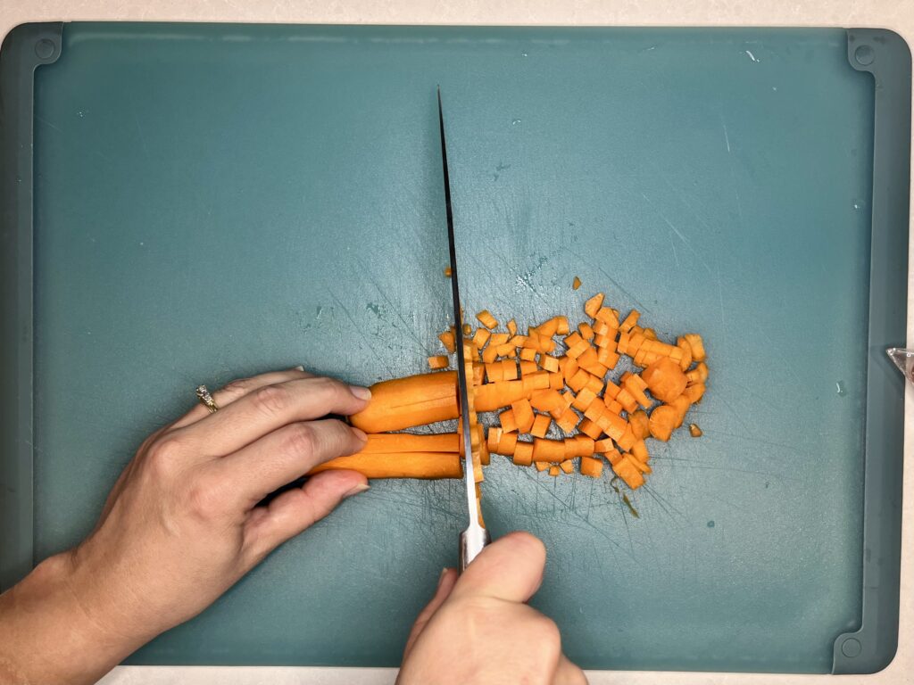 a knife finely chopping carrots