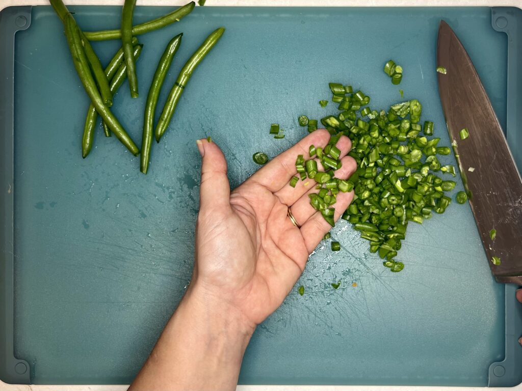 a hand holding finely chopped green beans