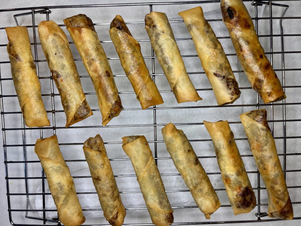 cooked lumpia draining on a rack