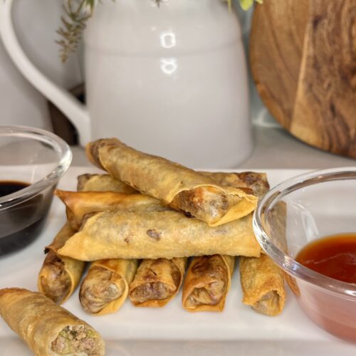 a plate with cooked lumpia and dipping sauces