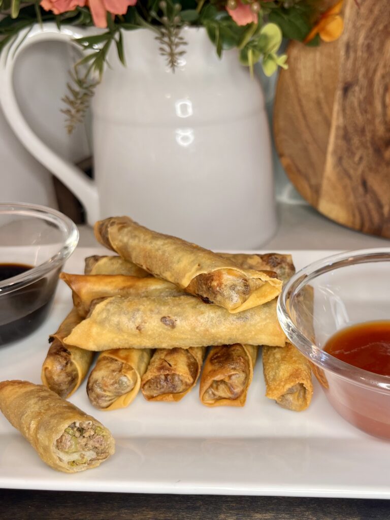 a plate with cooked lumpia and dipping sauces