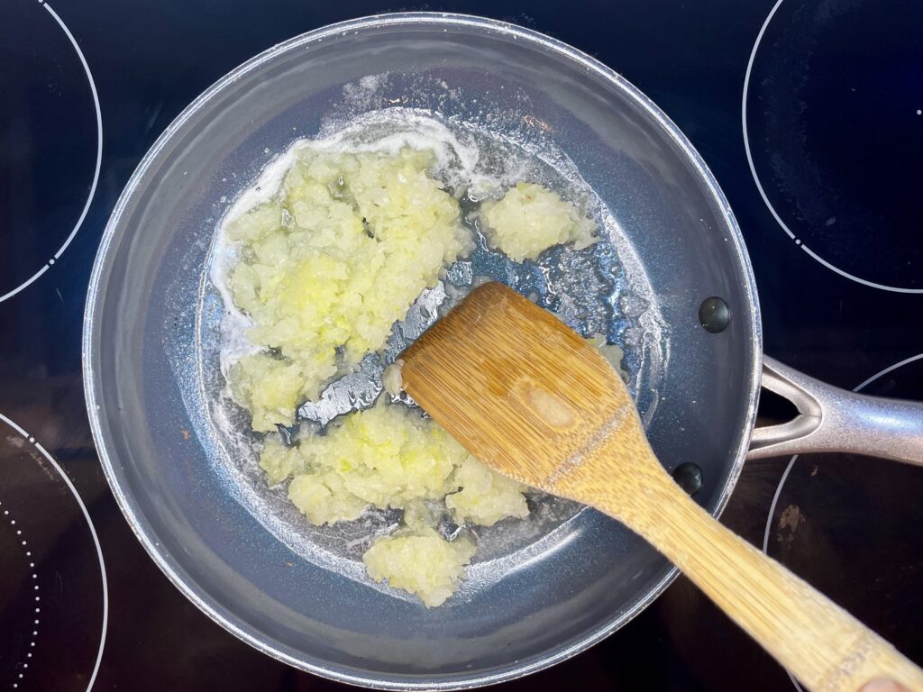 onions being cooked in a pan with melted butter