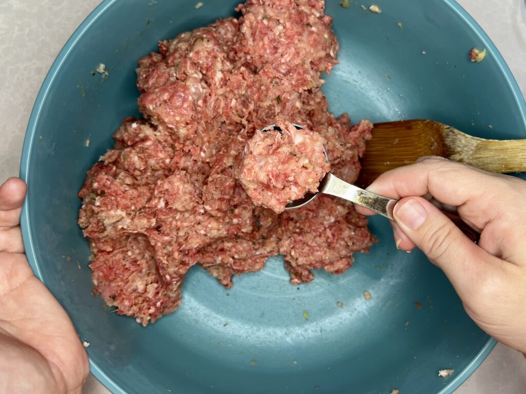 a tablespoon of meatball mixture being measured