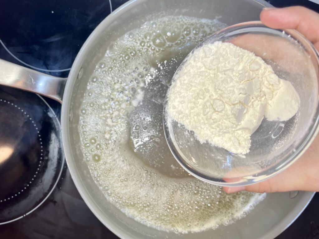 flour being added to melted butter in a pan 