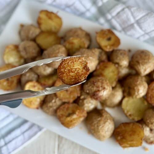 Crispy Parmesan potatoes served on a white platter, perfect for side dishes or snacks, showcasing golden-brown, seasoned potato bites with a cheesy crust.