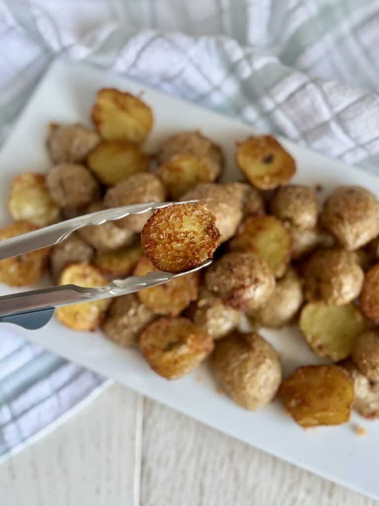 Crispy Parmesan potatoes served on a white platter, perfect for side dishes or snacks, showcasing golden-brown, seasoned potato bites with a cheesy crust.